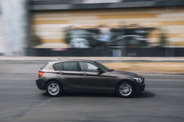 Ukrayna, Kyiv - 27 Haziran 2021: Kahverengi BMW 1 Serisi arabası sokakta hareket ediyor. Yazı