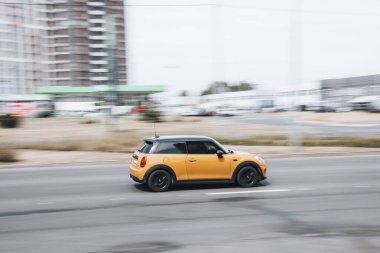 Ukrayna, Kyiv - 27 Haziran 2021: Sarı MINI Hatch arabası sokakta hareket ediyor. Yazı
