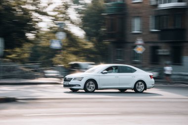 Ukrayna, Kyiv - 16 Temmuz 2021: Beyaz Skoda Superb arabası sokakta hareket ediyor. 