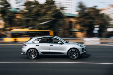 Ukrayna, Kyiv - 16 Temmuz 2021: Gümüş Porsche Macan arabası sokakta hareket ediyor. 