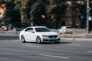 Ukrayna, Kyiv - 16 Temmuz 2021: Beyaz BMW 7 Serisi arabası sokakta hareket ediyor. 