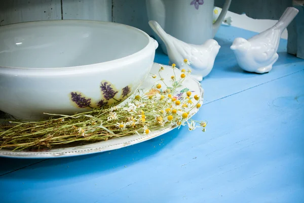 Utensílios de cozinha de cerâmica branca e camomilas na velha madeira azul — Fotografia de Stock