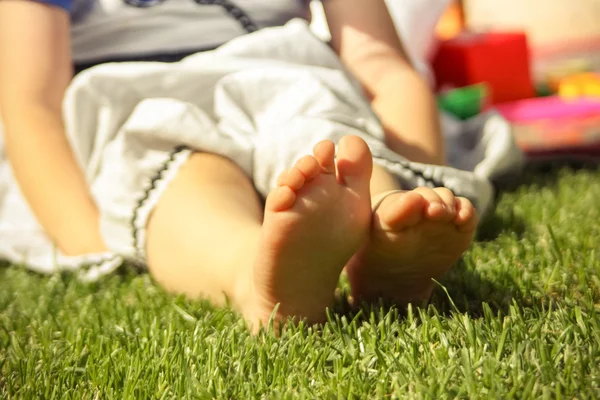 Small baby legs on the green grass — Stock Photo, Image