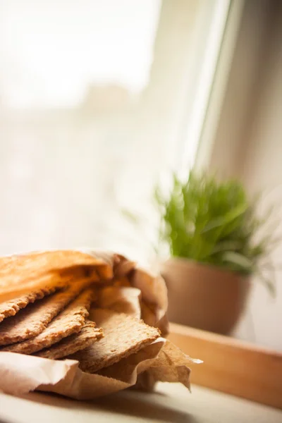 Tray with crispbreads and cup of grass  on the window sill — Stock Photo, Image