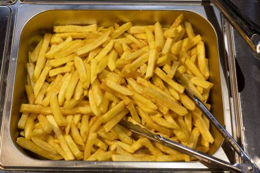 Açık büfe ya da restorandan servis edilecek büyük miktarda kızarmış patates kızartmasının yakın plan görüntüsü.