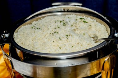 Mükemmel pişmiş beyaz pirinçle dolu, taze yeşil otlarla süslenmiş, yemek servisine hazır bir yemek tabağının yakından görüntüsü.