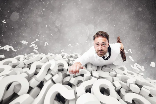 Zakenman klampt zich vast aan vraagtekens — Stockfoto