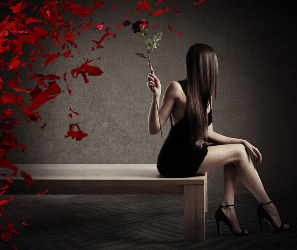 Woman sitting on a table with a red rose