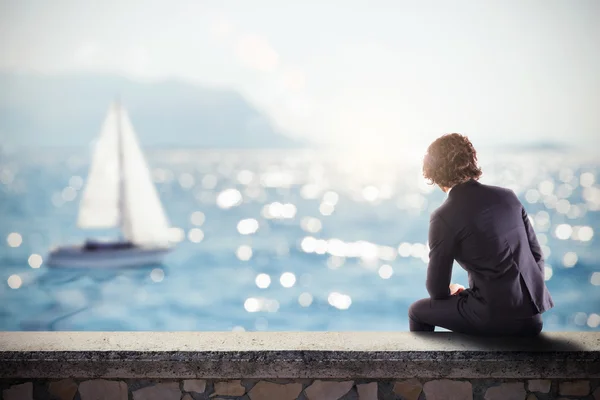 Hombre sentado en una pared mirando el mar — Foto de Stock