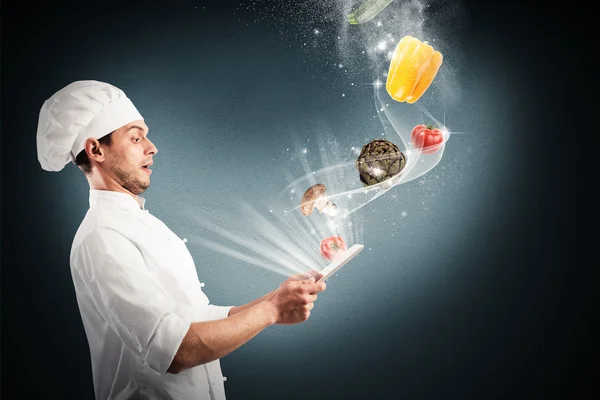 Chef looking at vegetables that come from tablet — Stock Photo, Image