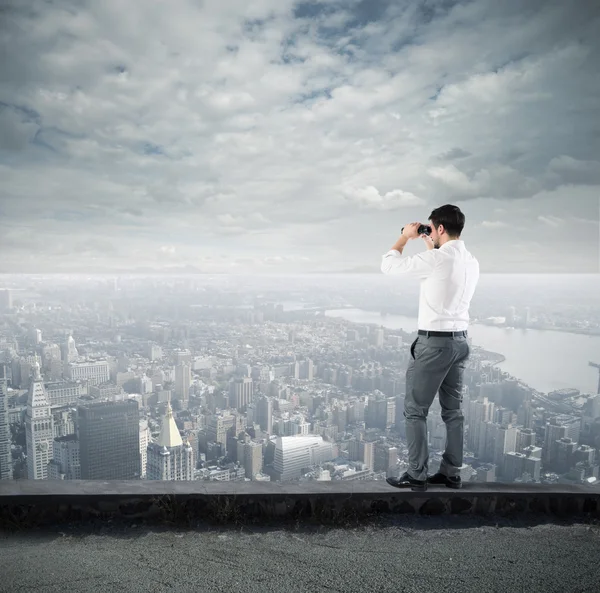 Uomo d'affari che guarda la città con binocolo — Foto Stock