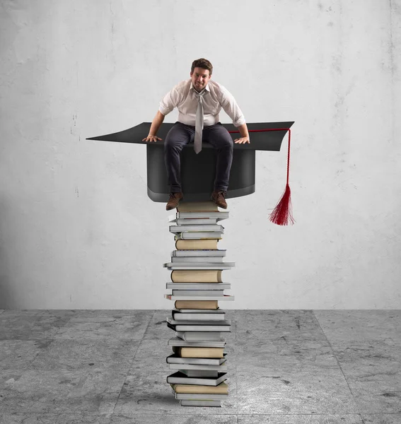 Businessman sitting on a pile of books — Stock Photo, Image