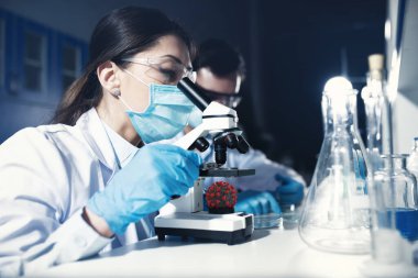 Laboratuvardaki doktorlar örnekleri mikroskop altında analiz ediyorlar. İlaç tedavisi konsepti
