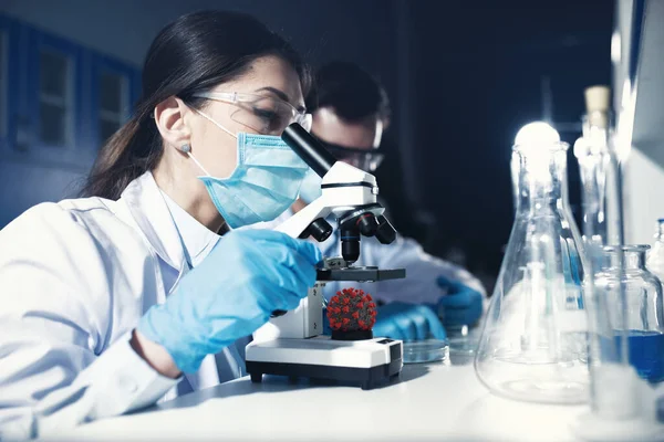 Laboratuvardaki doktorlar örnekleri mikroskop altında analiz ediyorlar. İlaç tedavisi konsepti