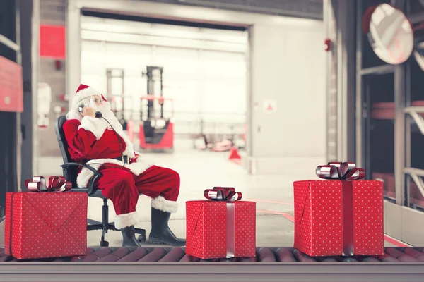Mikulás elfoglalt a megrendelések karácsonyi ajándékok egy raktárban — Stock Fotó