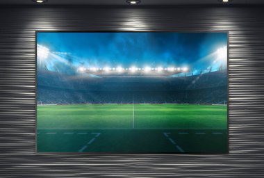 Sahne ışıklarıyla aydınlatılmış ve monte edilmiş büyük bir televizyon duvarında futbol maçı izlemek
