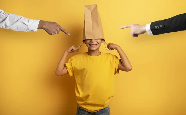 Kind is uitgescholden en verbergt zijn hoofd in een boodschappentas. — Stockfoto