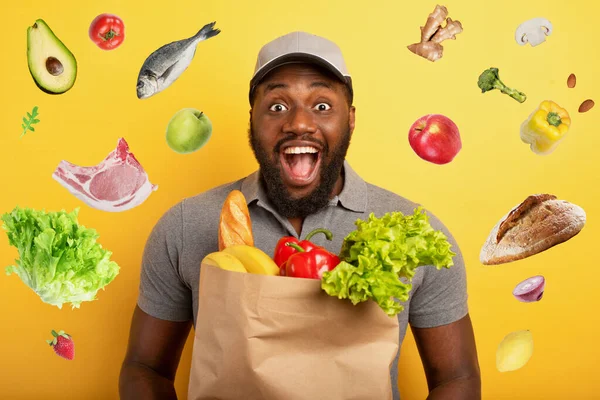 食品と袋を提供する準備ができて幸せな表情を持つ配達人。黄色の背景. — ストック写真