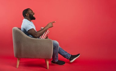 Adam film izlerken eğleniyor. Eğlence ve televizyon yayını kavramı. kırmızı arkaplan