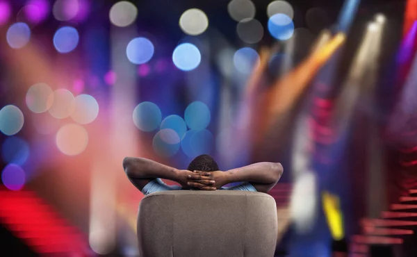 Man relaxing on a armchair and watches a show in a theatre — Stock Photo, Image