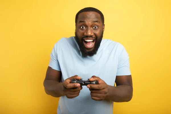 Happy man speelt met een videogame op gele achtergrond — Stockfoto