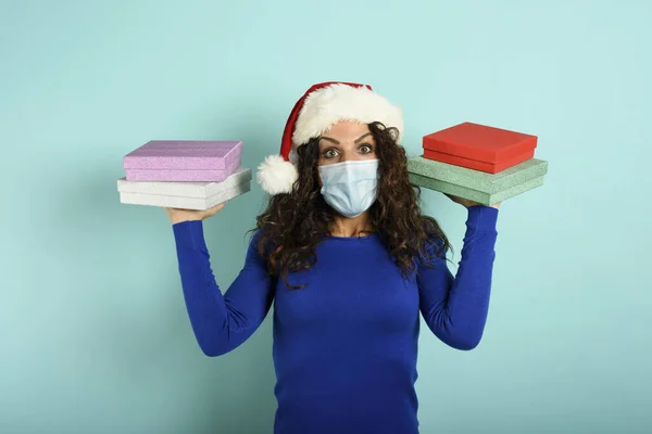 Glückliches Mädchen mit Gesichtsmaske erhält Weihnachtsgeschenke. Cyan-Hintergrund — Stockfoto