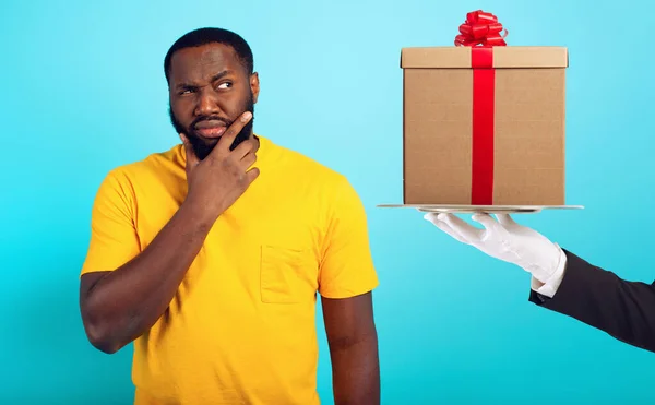 Confused man is suspicious about a gift. concept of options, confusion, indecision — Stock Photo, Image