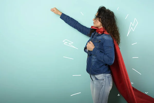 Vrouw gedraagt zich als een superheld. Concept van vastberadenheid en macht. Cyaan achtergrond — Stockfoto