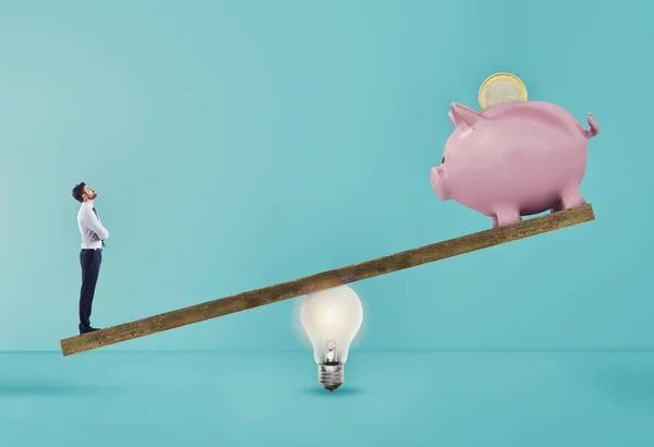 Empresário usa alavanca de anúncio de lâmpada para levantar o banco de pombos. Conceito de renda fácil com uma boa ideia. Contexto ciano — Fotografia de Stock