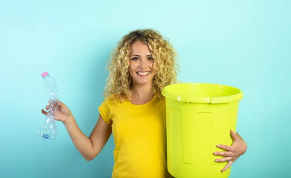 Frau ist bereit, eine Plastikflasche in den Mülleimer zu legen. Cyan-Hintergrund — Stockfoto