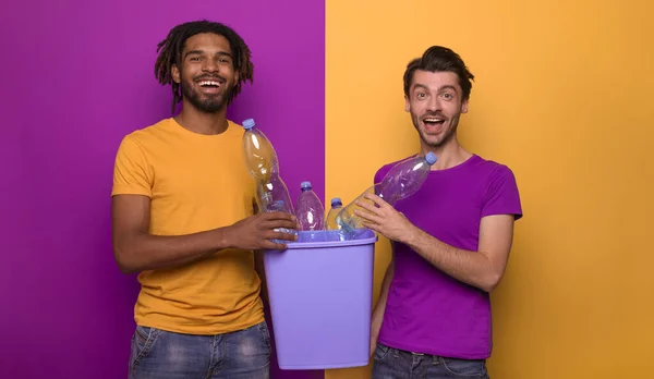 Freunde halten einen Plastikbehälter mit Flaschen über gelber und lila Farbe. Konzept von Ökologie, Naturschutz, Recycling und Nachhaltigkeit — Stockfoto