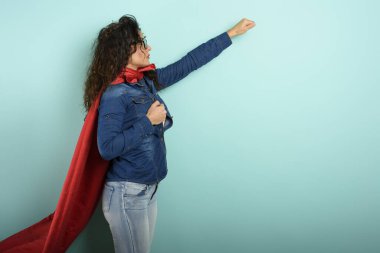 Kadın süper kahraman gibi davranıyor. Kararlılık ve güç kavramı. Cyan arkaplanı