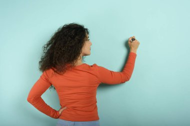 Woman write something with a pen. Blank space for your text. Cyan background