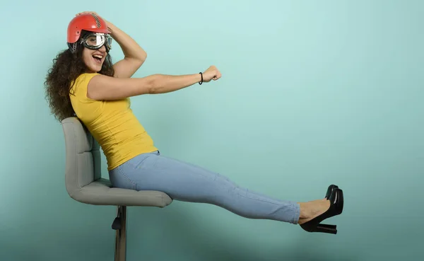Mulher com capacete vermelho pensa em dirigir um carro rápido. fundo ciano. — Fotografia de Stock