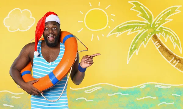 Hombre negro en traje de baño listo para ir en un lugar soleado para Navidad. Fondo amarillo — Foto de Stock