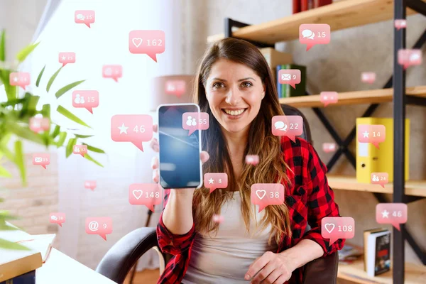 Mujer feliz muestra su teléfono inteligente con mensajes de redes sociales, chat y usuarios iconos — Foto de Stock