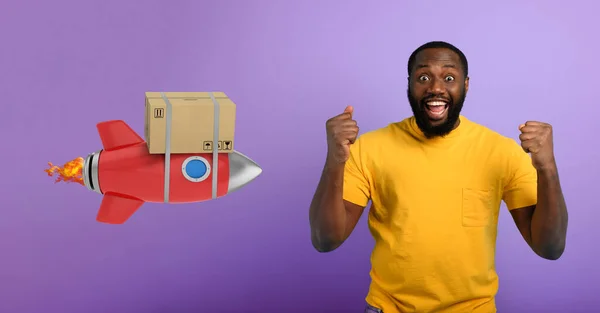 El hombre negro está feliz de recibir un paquete. Concepto de entrega rápida como un cohete. Fondo púrpura — Foto de Stock
