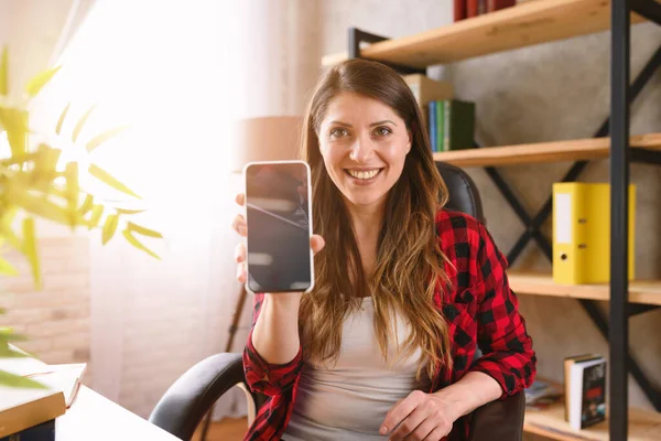 Šťastná žena ukazuje něco ve svém moderním smartphonu — Stock fotografie