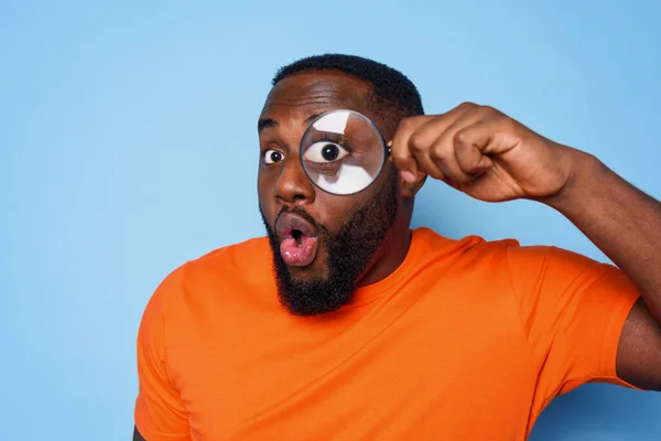 Hombre buscar algo con una lente de lupa con expresión sorprendida —  Fotos de Stock