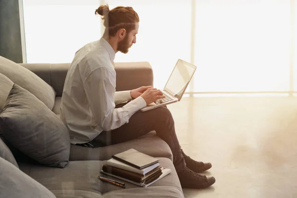 El hombre de negocios trabaja en el sofá con su portátil. él está en el trabajo inteligente — Foto de Stock