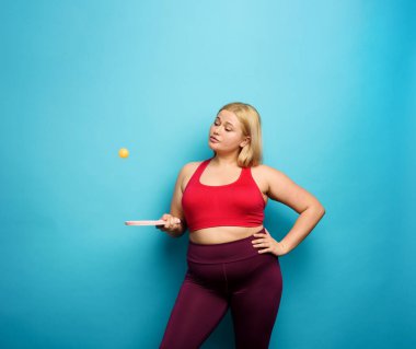 Şişman kız masa tenisiyle oynamaya çalışıyor. Cyan arkaplanı