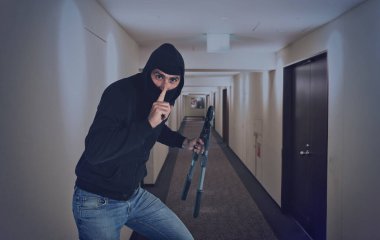 Kar maskeli bir hırsız, elinde tel kesici olan daireleri çalmak için sessizce hareket eder.