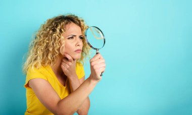 Büyüteçli bir kız bir şeye güvenmiyor. Cyan arkaplanı