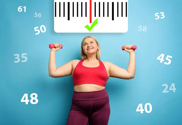 Chica gorda hace gimnasia en casa con expresión satisfecha porque disminuye su peso. Antecedentes cian —  Fotos de Stock