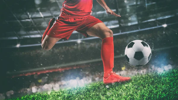 Крупним планом футбольну сцену в нічному матчі з гравцем у червоній формі, штовхаючи м'яч силою — стокове фото