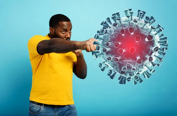 Adam koronavirüse bir yumrukla saldırıyor. Mavi arkaplan — Stok fotoğraf