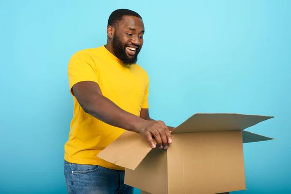 Happy man dostává balíček z online obchodu. Šťastný výraz. Modré pozadí. — Stock fotografie