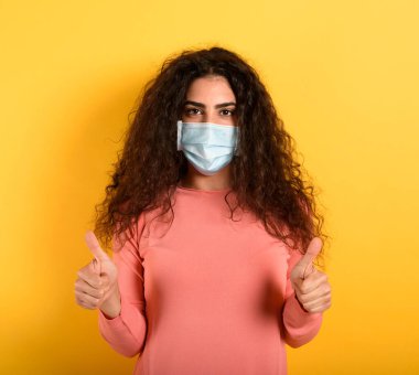 Kız covid 19 koronavirüsün yenilmesi konusunda iyimser. sarı arkaplan.