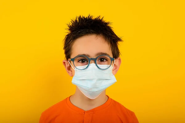 Portrait of a child with face mask for covid-19 coronavirus. yellow background — Stock Photo, Image