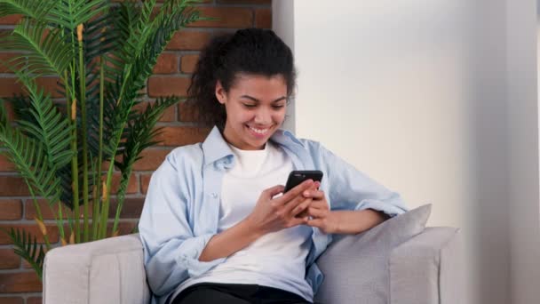 Mujer charla con amigos con su teléfono inteligente en un sillón — Vídeo de stock